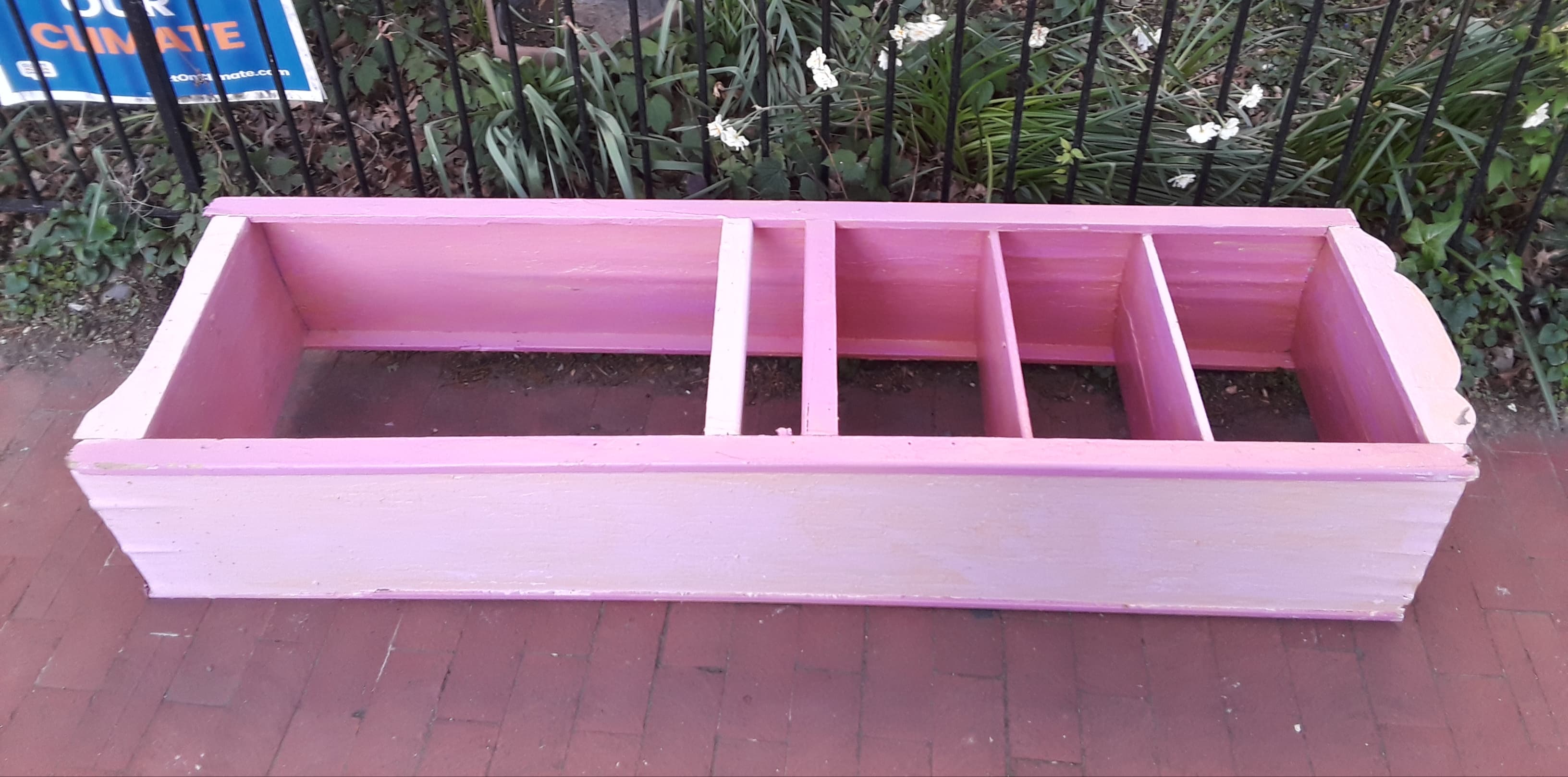 Pink bookshelf lying on the sidewalk