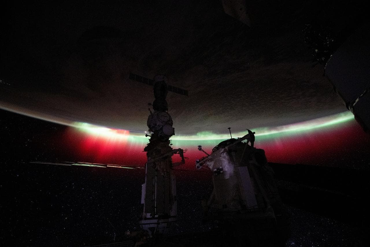 A vibrant green and red aurora shimmers above New Zealand