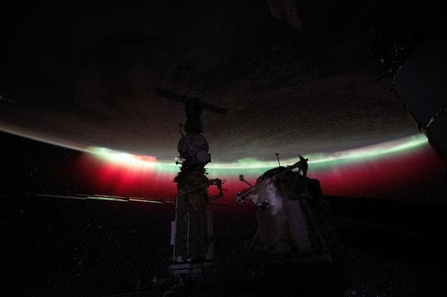 A vibrant green and red aurora shimmers above New Zealand