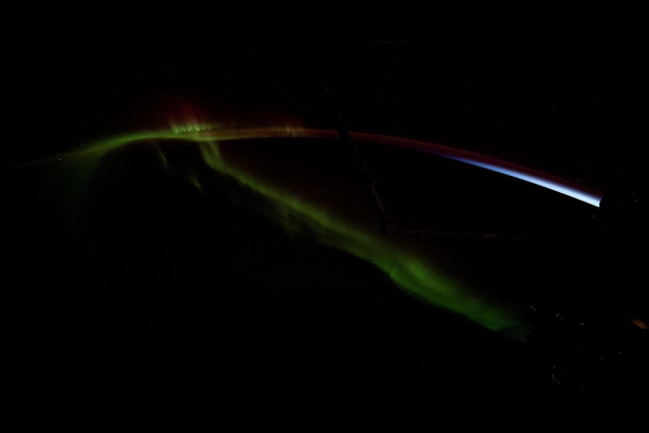 A wispy aurora australis streams over the Earth