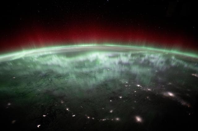 An aurora shimmers and dances above the city lights of Canada