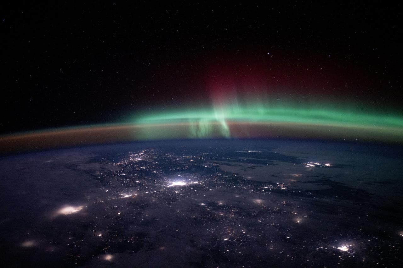 City lights dot the Canadian landscape underneath an aurora