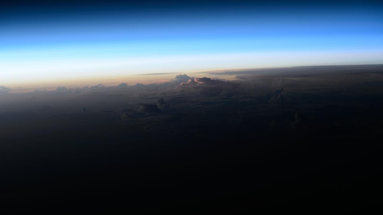 An orbital sunrise breaks above the clouds