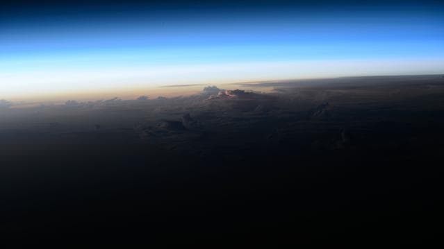 An orbital sunrise breaks above the clouds