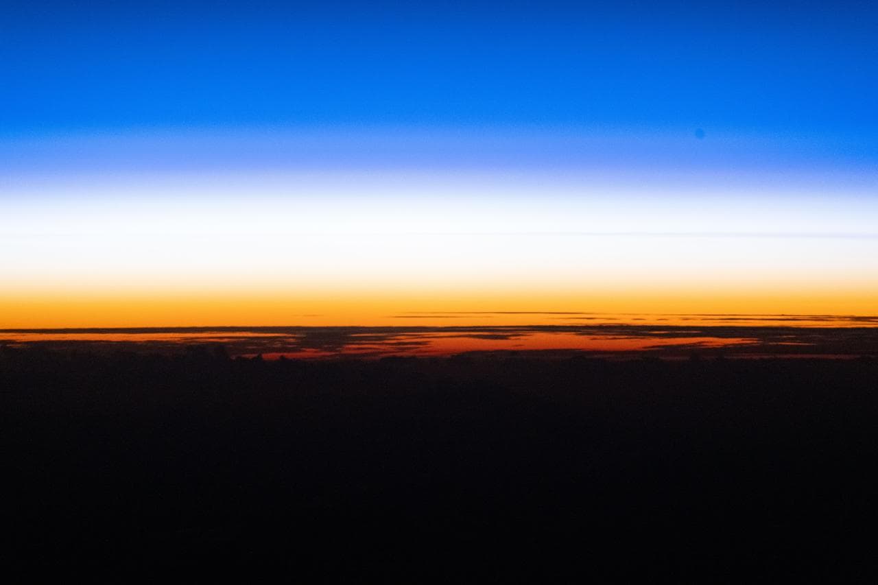 An orbital sunset silhouettes the cloud tops above the Pacific Ocean
