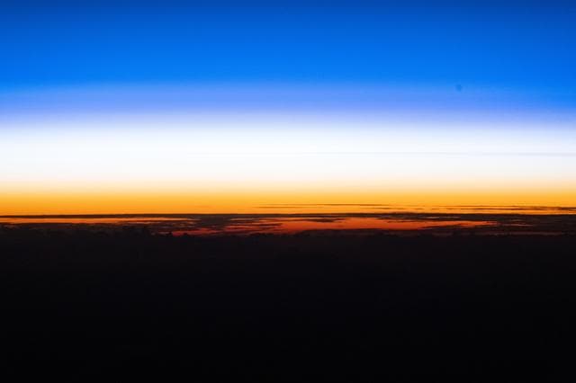 An orbital sunset silhouettes the cloud tops above the Pacific Ocean