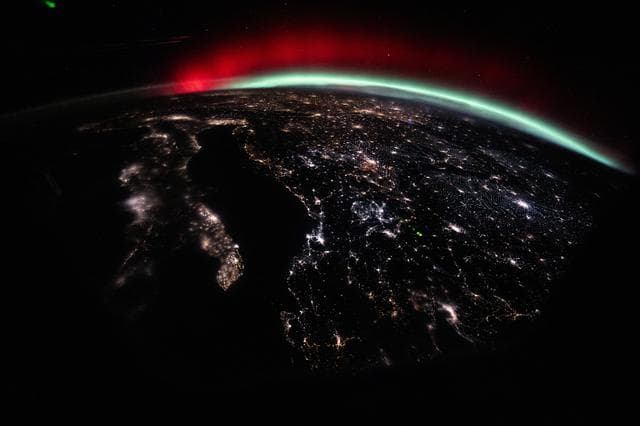 A green and red aurora streams across Earth’s horizon above Europe