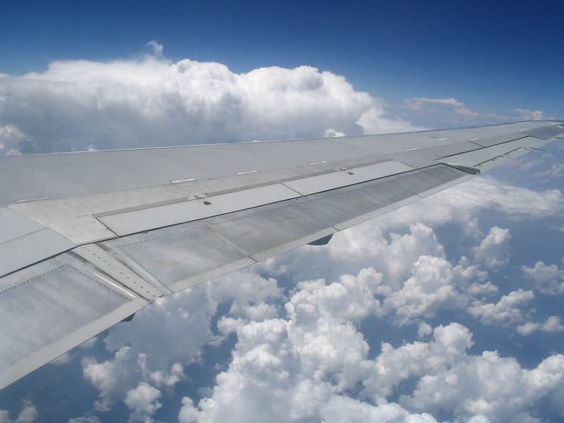 Airplane wing in front of cumulus clouds