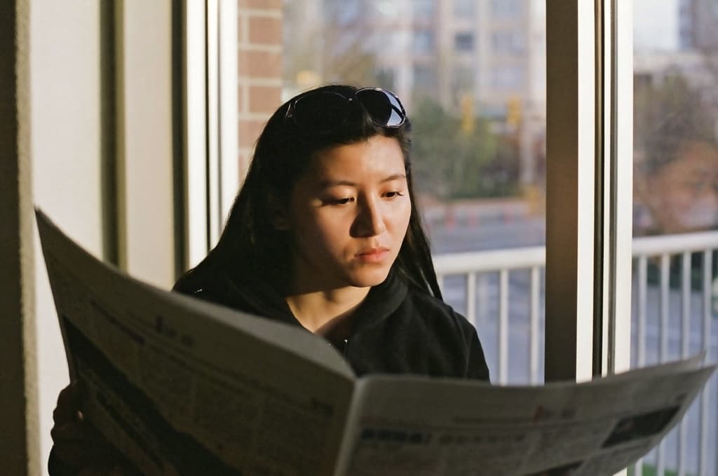 Reading Newspaper at Window