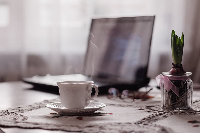 A cup of coffee, a flower and a laptop