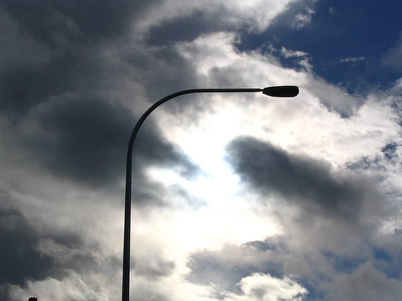 Sun behind clouds framed by lamppost