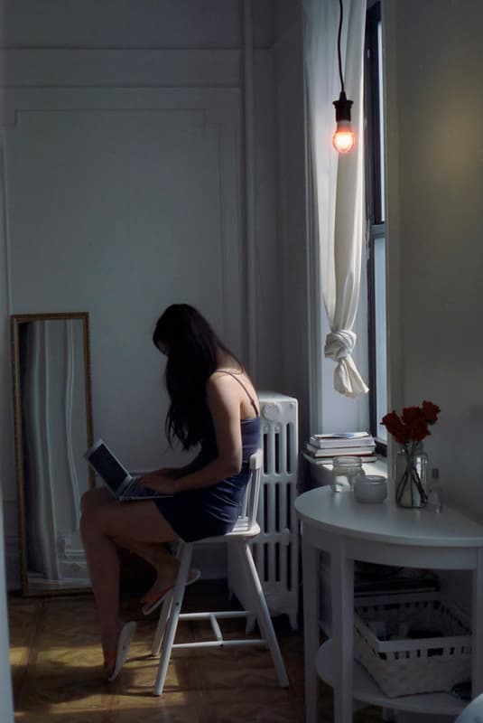 Girl using laptop by window