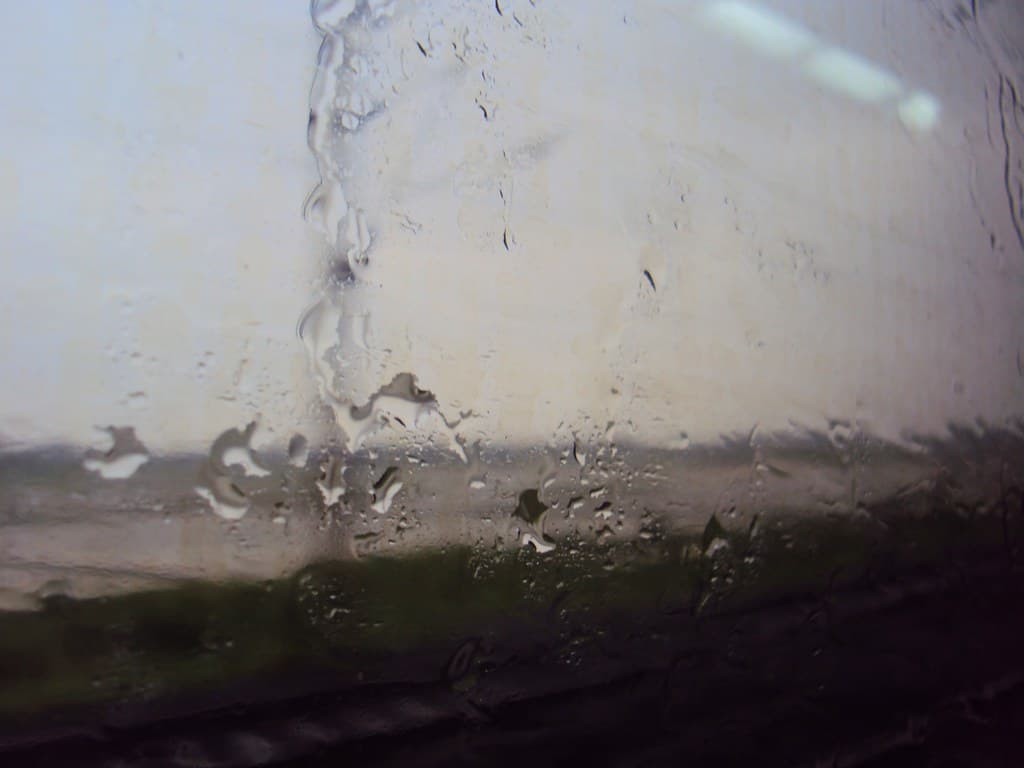Rainwater trickles down outside the window