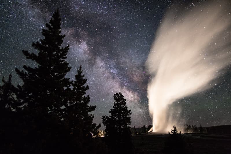 Old Faithful erupts under a clear summer sky