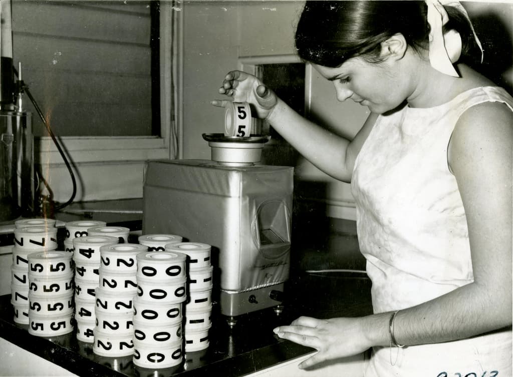 Checking weight of disks from Golden Casket machine, 1967
