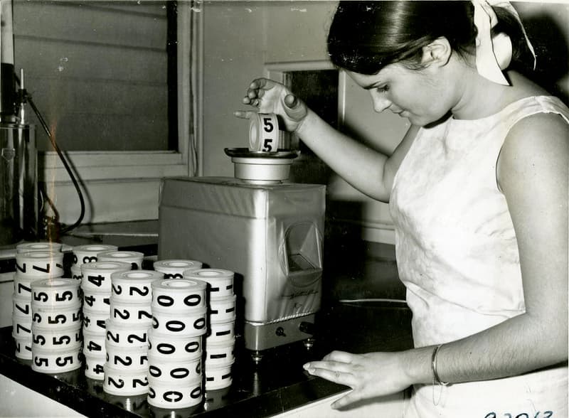 Checking weight of disks from Golden Casket machine, 1967