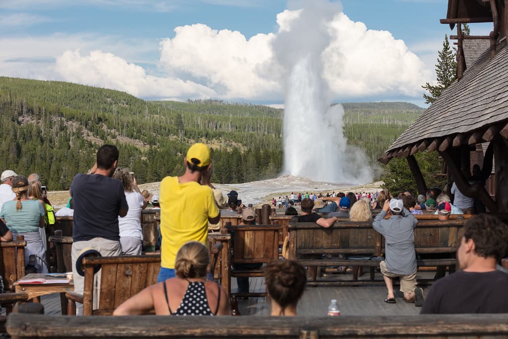 People watching Old Faithful erupt from the Old Faithful Inn