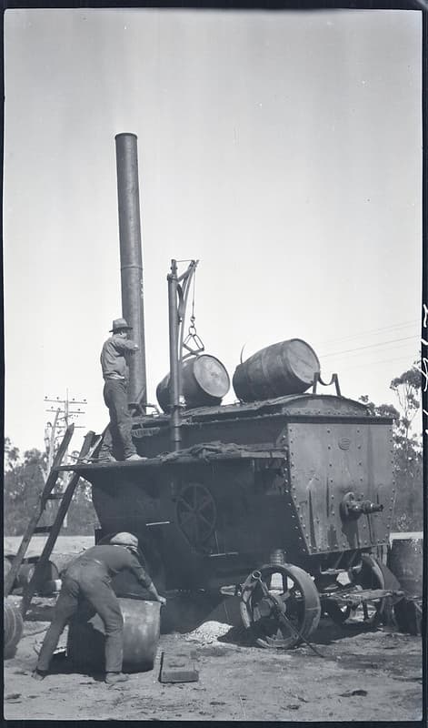 Men loading barrels of tar into tar melting machine