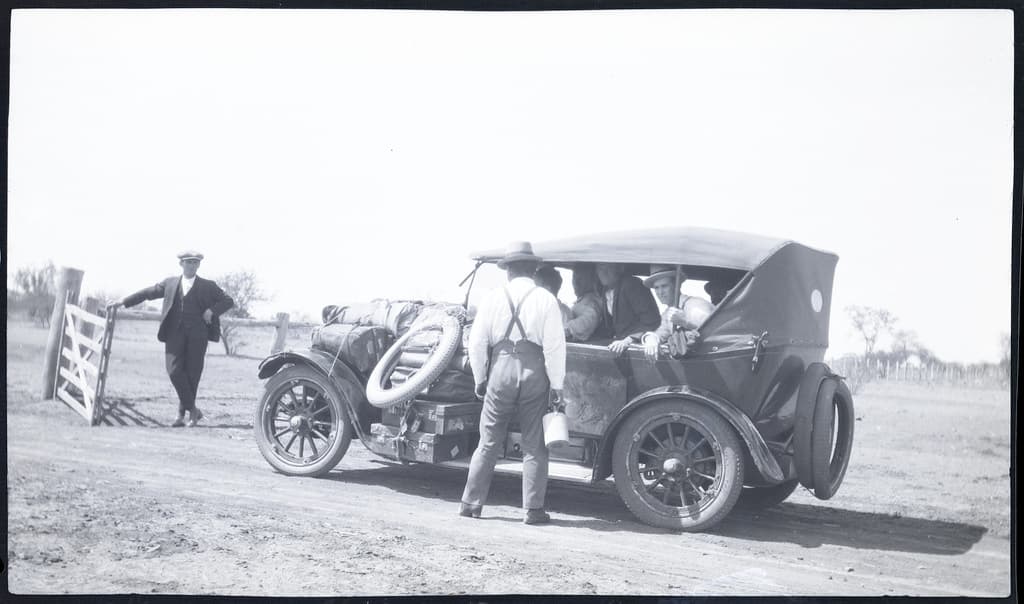 Man holding gate open for car.