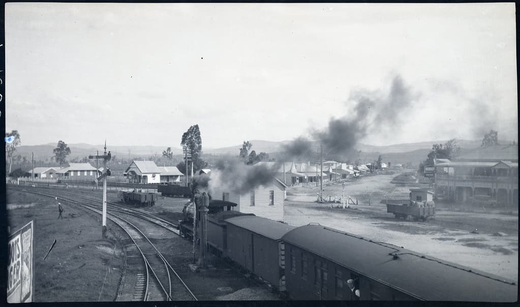 Steam train at Helidon railway station. Houses and shops in background