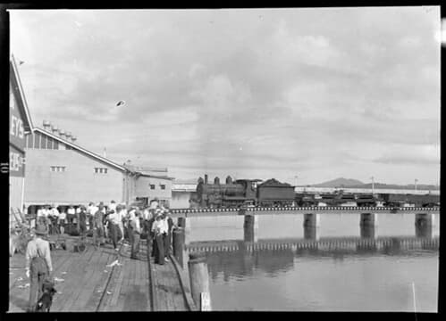 Crowd watching train cross bridge. c.1940