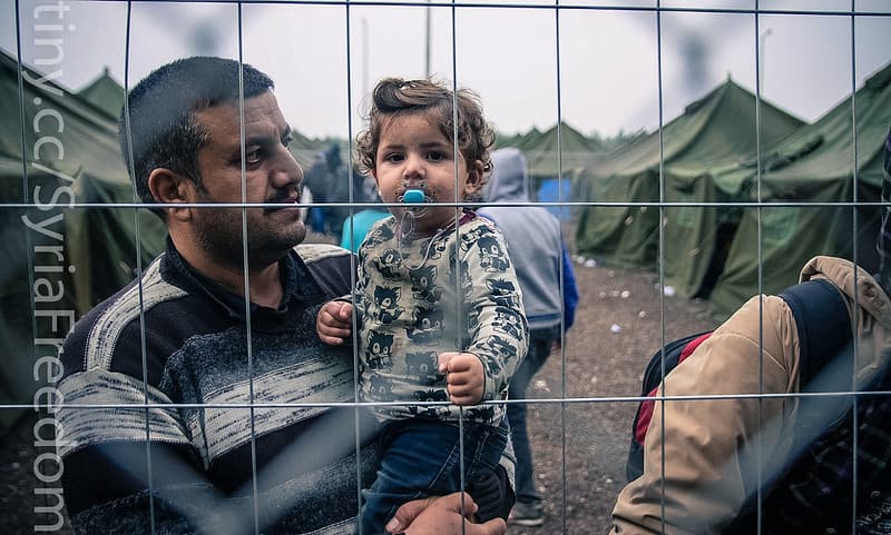 A Syrian refugee carrying his child