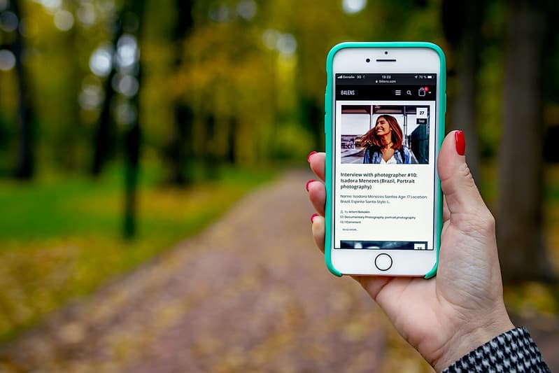 Woman hand with smartphone. Fall background.