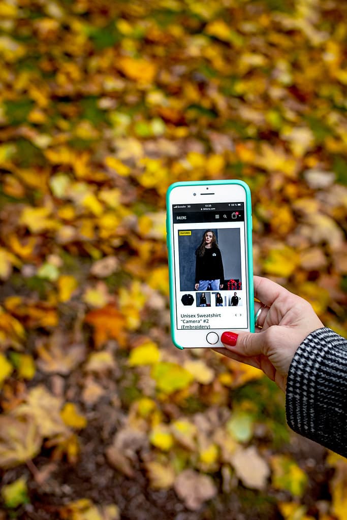 Woman hand with smartphone. Fall background.