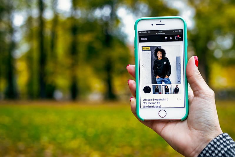 Woman hand with smartphone. Fall background.