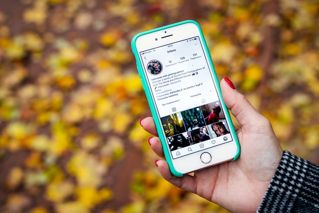 Woman hand with smartphone. Fall background.
