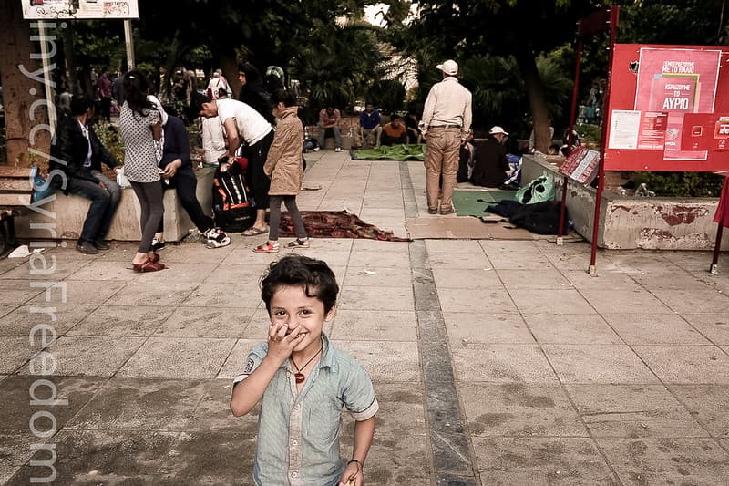 A refugee child stands in an Athens central square