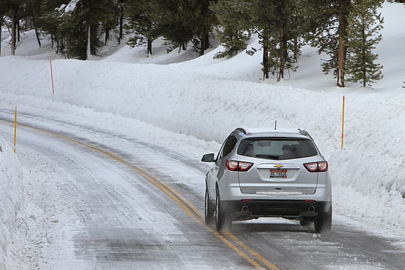 Car driving on Northeast Entrance Road lined with tall snowbanks