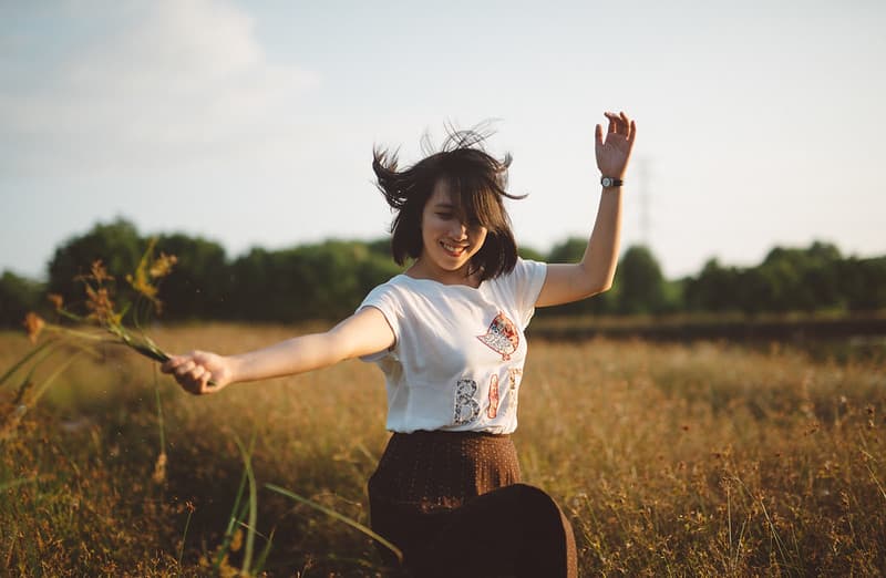 Female Holding Flowers Dancing in Field