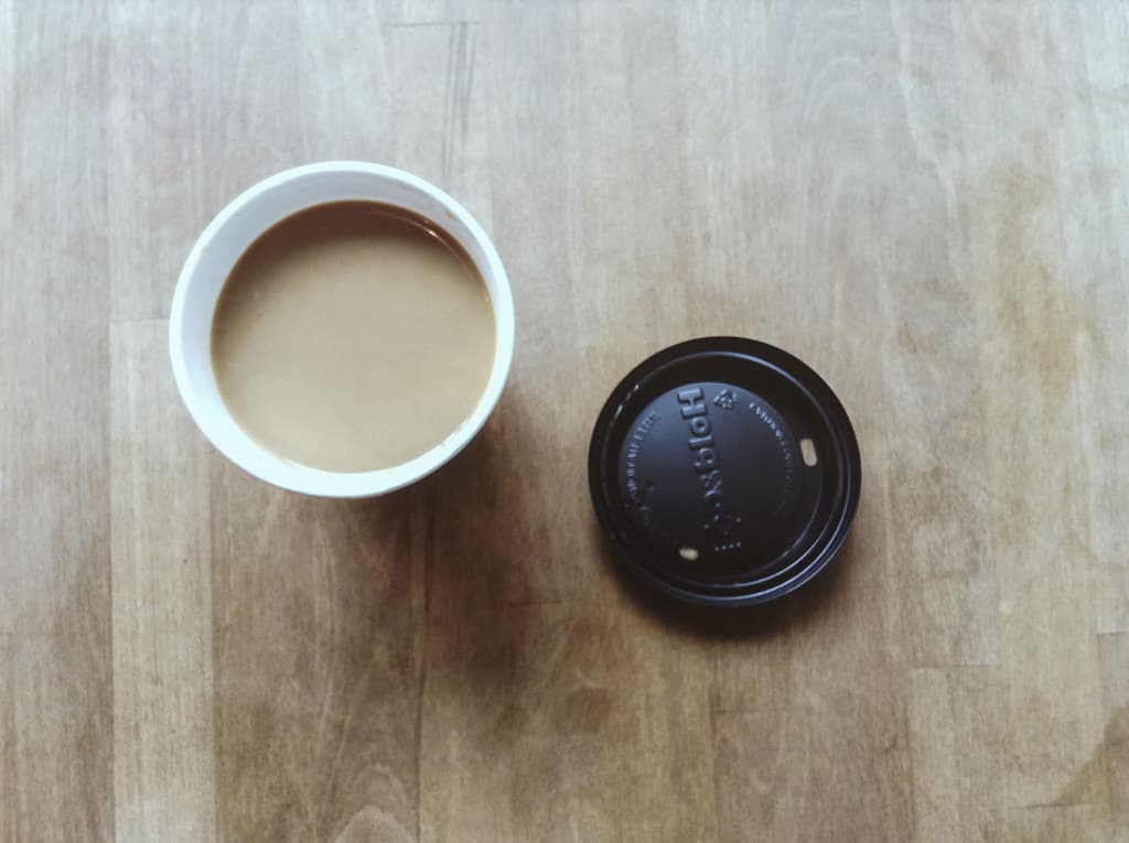 Cup of Coffee and Lid on Wood Tabletop