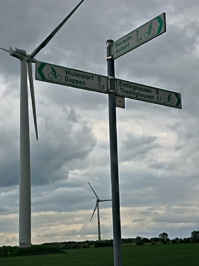 Green cycle route sign and wind turbines