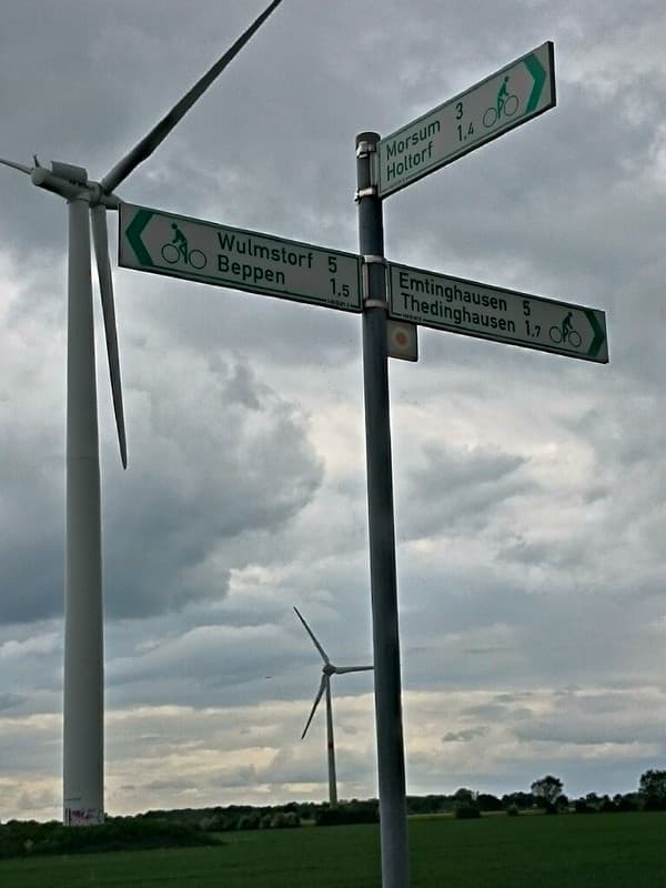 Green cycle route sign and wind turbines