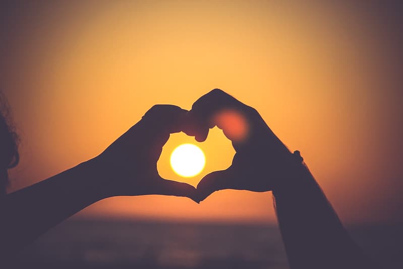 Two Hands Making a Heart with Sunset in Background