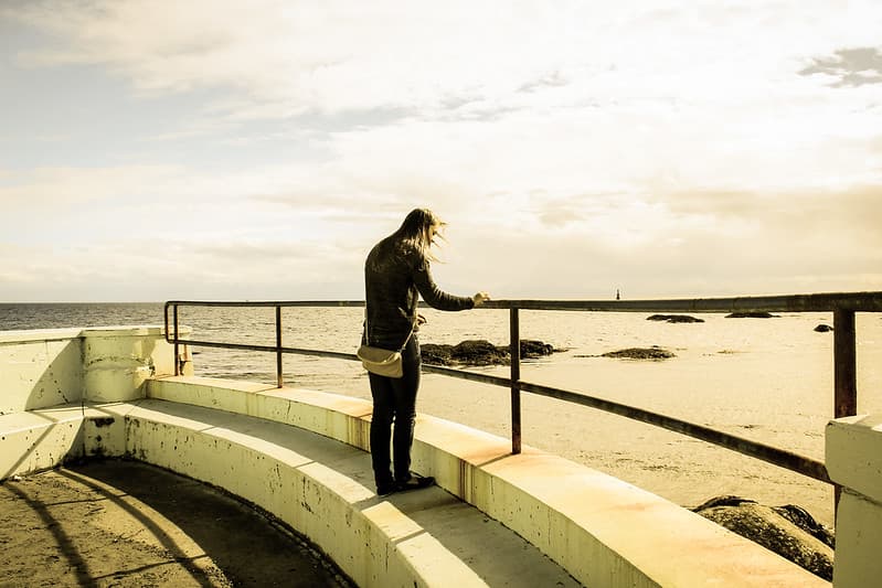 Female Standing by Fence Overlooking Ocean
