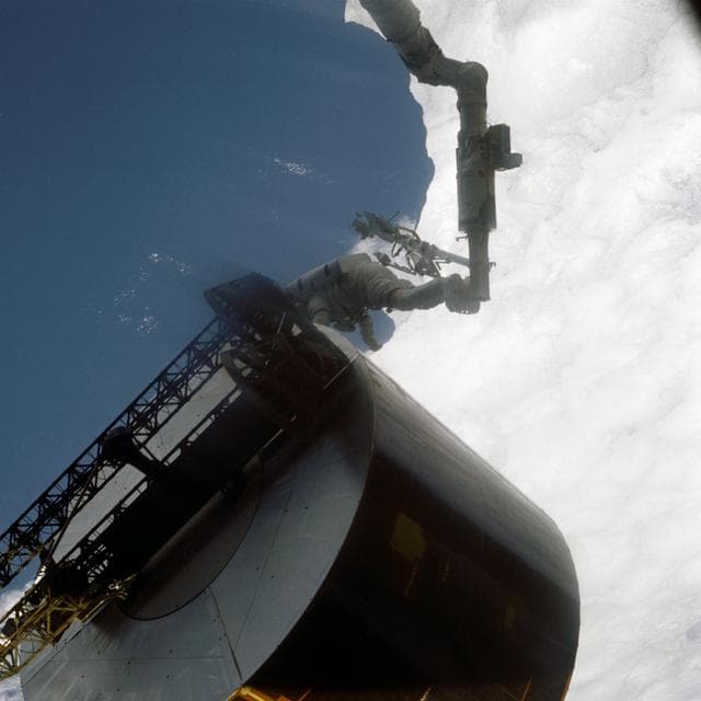 Astronaut James van Hoften working with Syncom IV-3 satellite