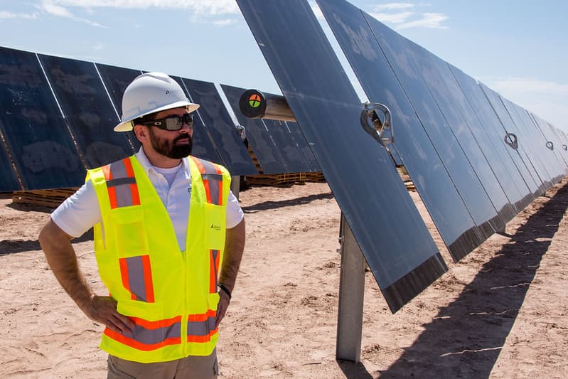 Ray Castro stands next to solar panels