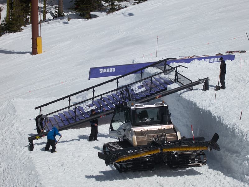 Prinoth snow groomer and blue portable staircase
