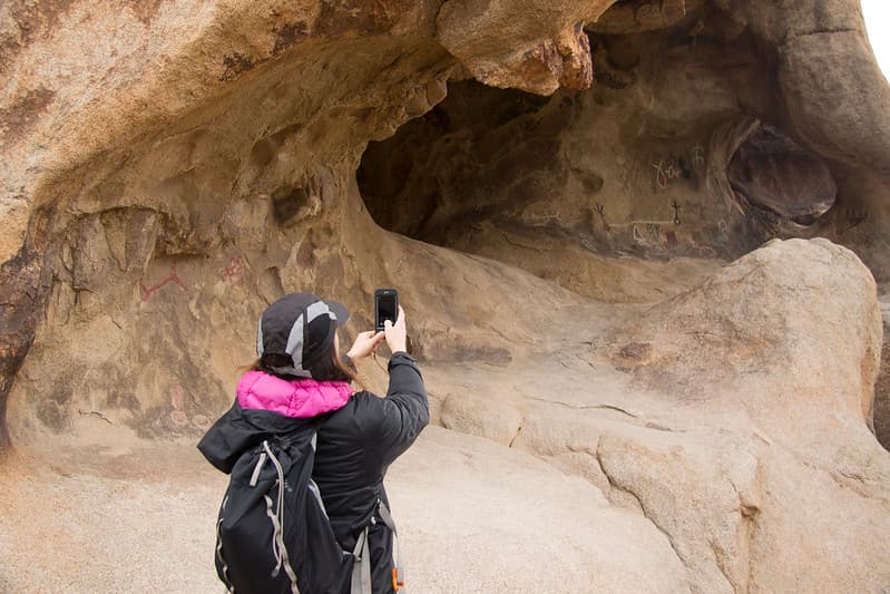 Visitor photographing petroglyphs/pictographs with smartphone